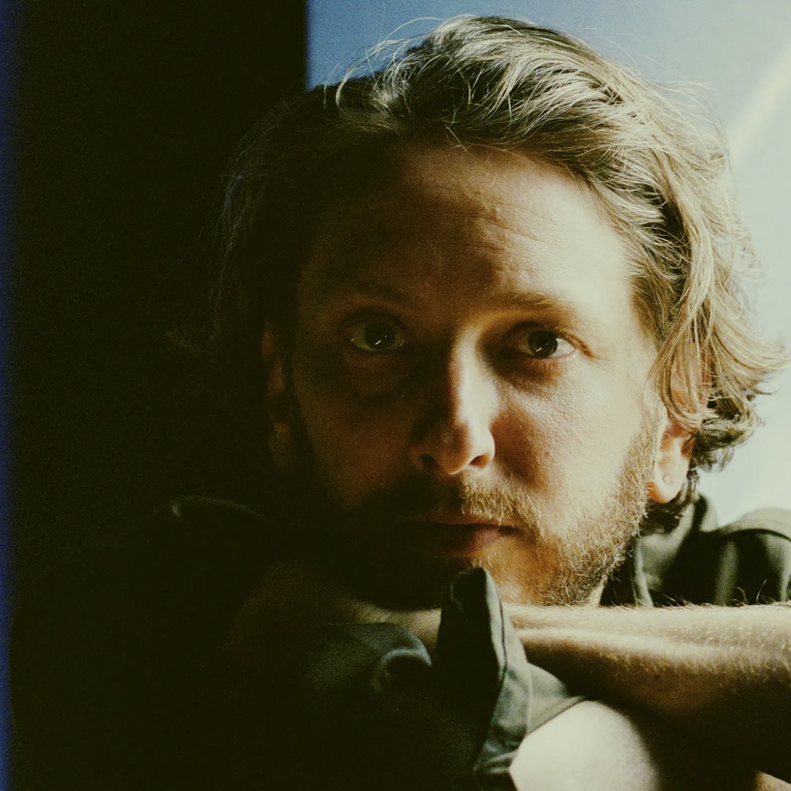 Close-up portrait of Daniel Lopatin, also known as Oneohtrix Point Never, featuring his wavy light brown hair and introspective gaze.