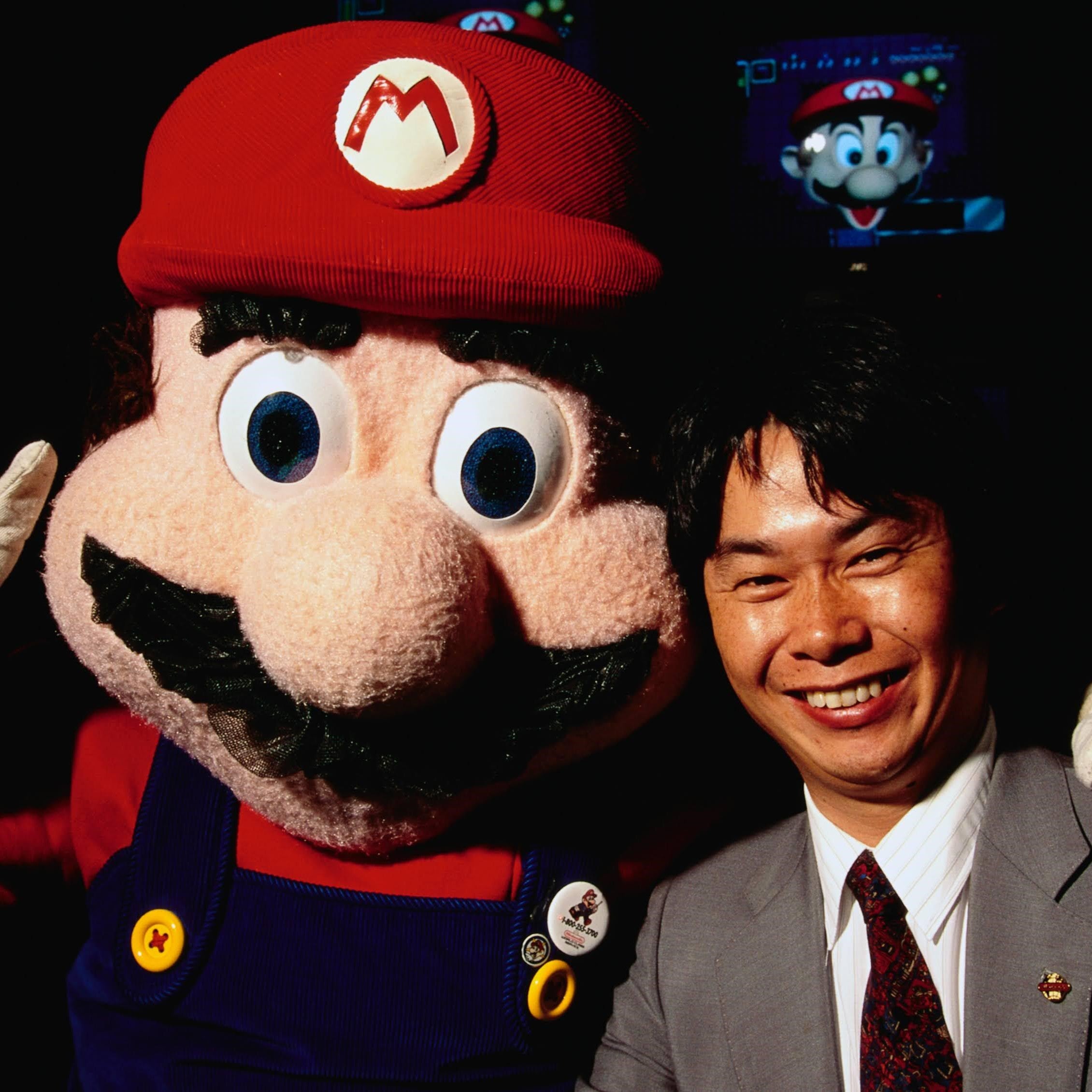 Iconic photo of Shigeru Miyamoto, the legendary video game designer, smiling alongside a life-sized Mario mascot.