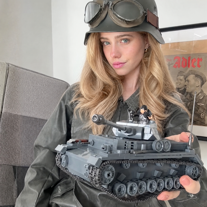 A woman in a steel helmet and goggles holding a grey brick tank