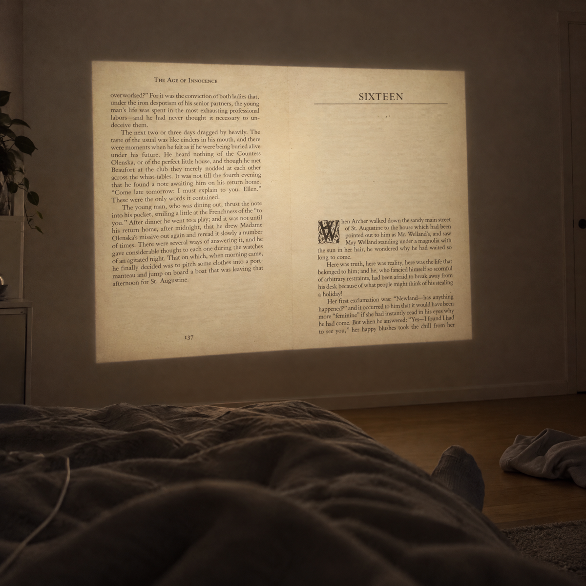 A book page projected on the bedroom wall, photographed from bed at night